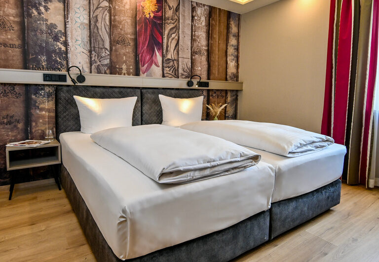 Das gemütliche Bett im stilvollen Schlafzimmer des Basic-Zimmers im Hotel Dreiflüssehof, mitten im Bayerischen Wald.