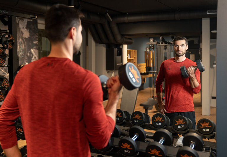 Fitness im Hotel Dreiflüssehof – Mann trainiert mit Hanteln im hauseigenen Fitnessbereich