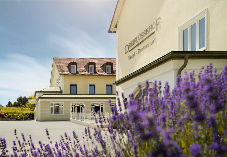 Außenansicht des idyllischen Hotelgebäudes Dreiflüssehof mit blühendem Lavendel im Vordergrund.