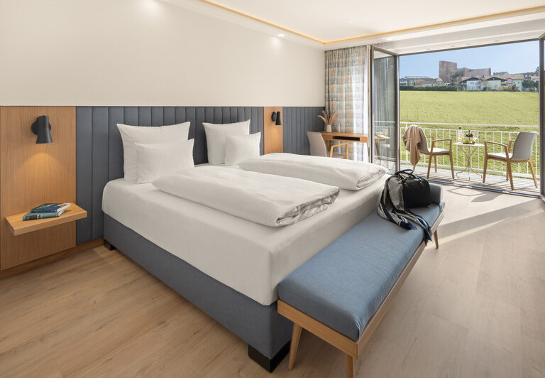 Stilvolles Schlafzimmer des Superior-Zimmers im Dreiflüssehof mit Zugang zum Balkon, der eine hervorragende Aussicht bietet.